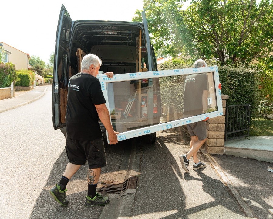 Deux menuisiers Otentik sortant une grande fenêtre du camion