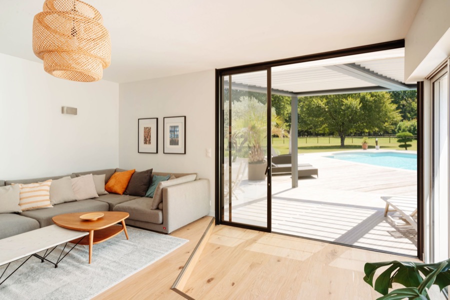 Grande baie vitrée aluminium ouverte sur une terrasse et une piscine