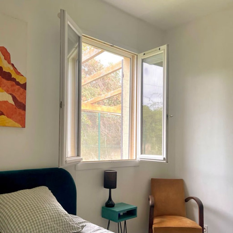Moustiquaire plissée sur une fenêtre ouverte de chambre