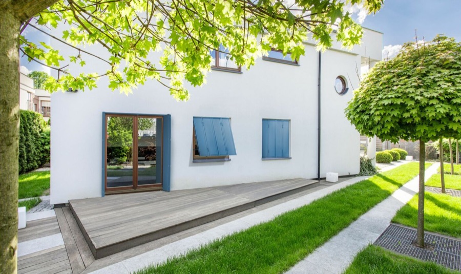 Persiennes repliables sur une maison blanche avec terrasse en bois