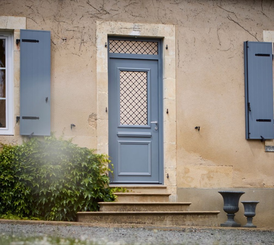 Porte d'entrée bleue à imposte vitrée sur une façade en pierre