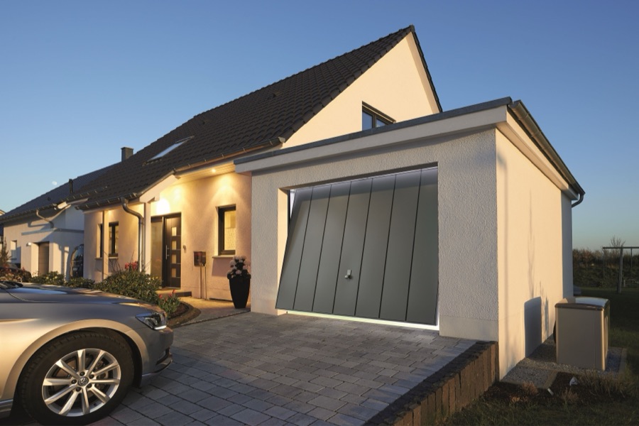 Porte de garage basculante gris anthracite sur une maison au crépuscule