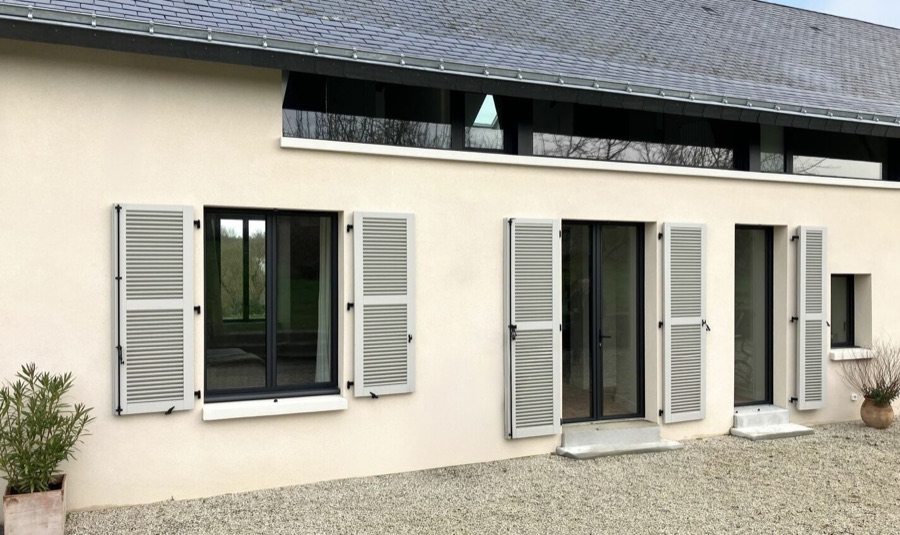 Volets battants en bois gris clair sur une longère rénovée